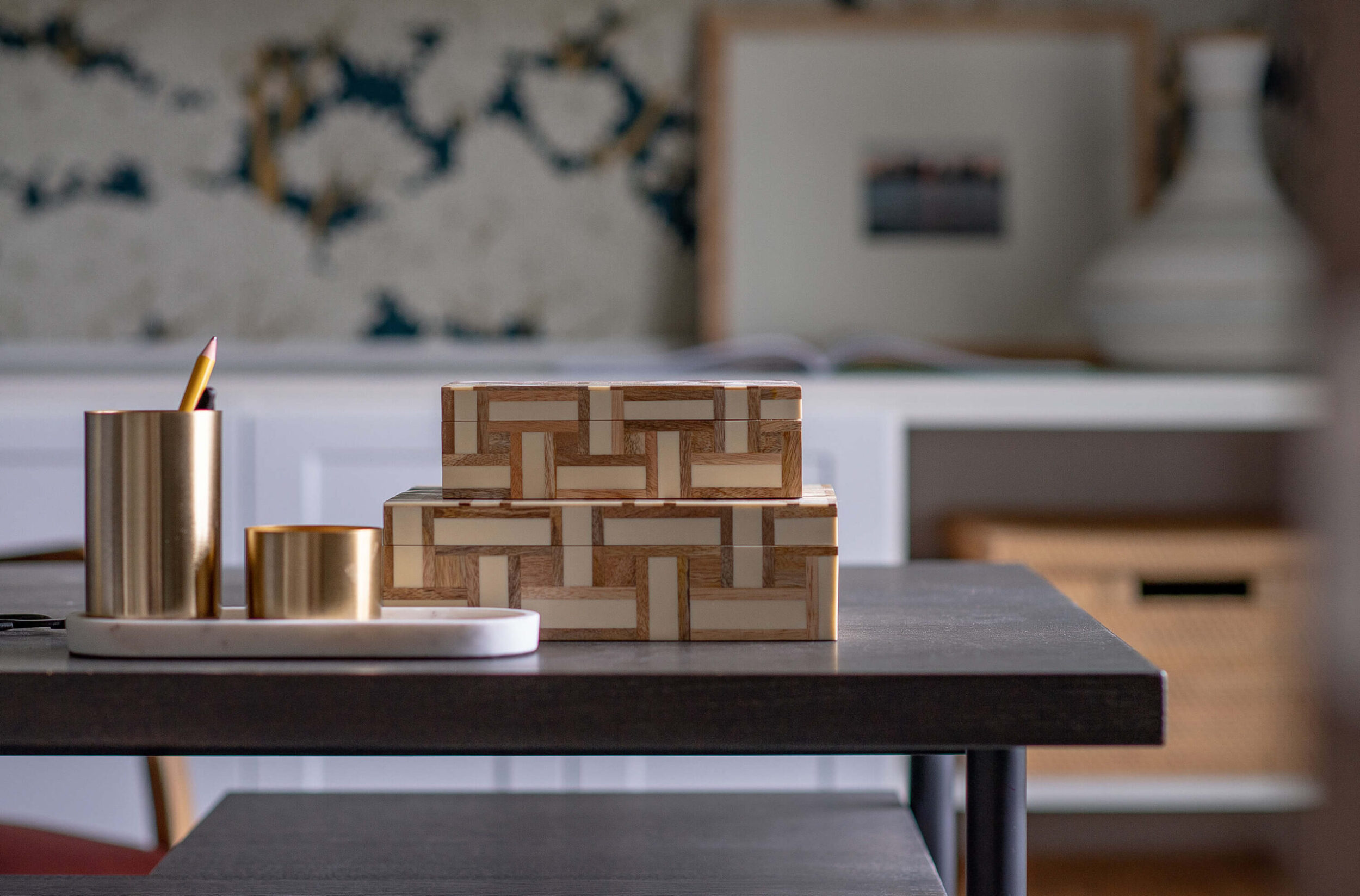 Close-up of decorative desk accessories with gold pen holders and patterned boxes in modern home office.