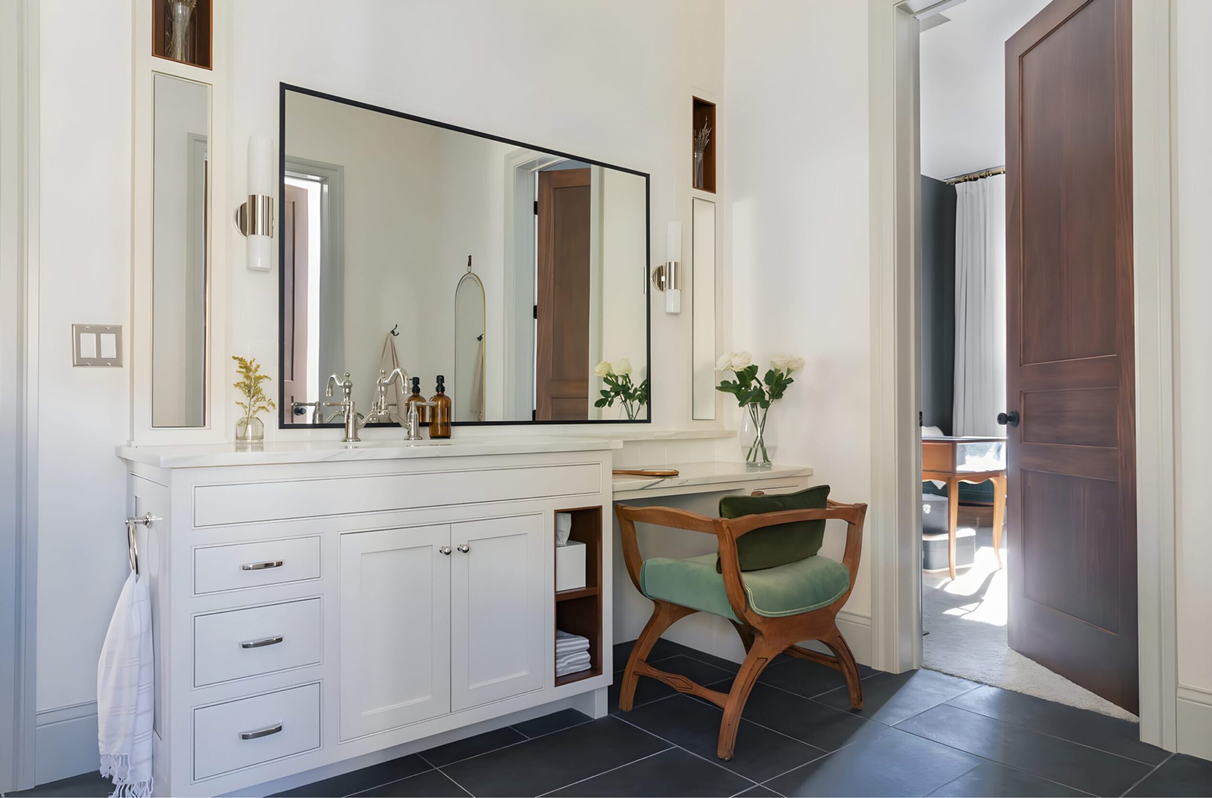 Elegant bedroom with plush bedding, modern light fixture, and calming tones accented by greenery and natural textures.