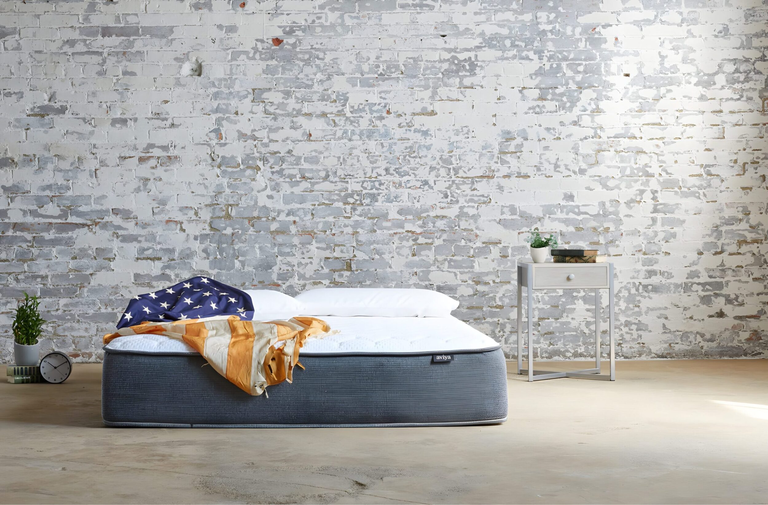 Minimal bedroom set styling with mattress, wood headboard, side table, and books styled for commercial interior shoot