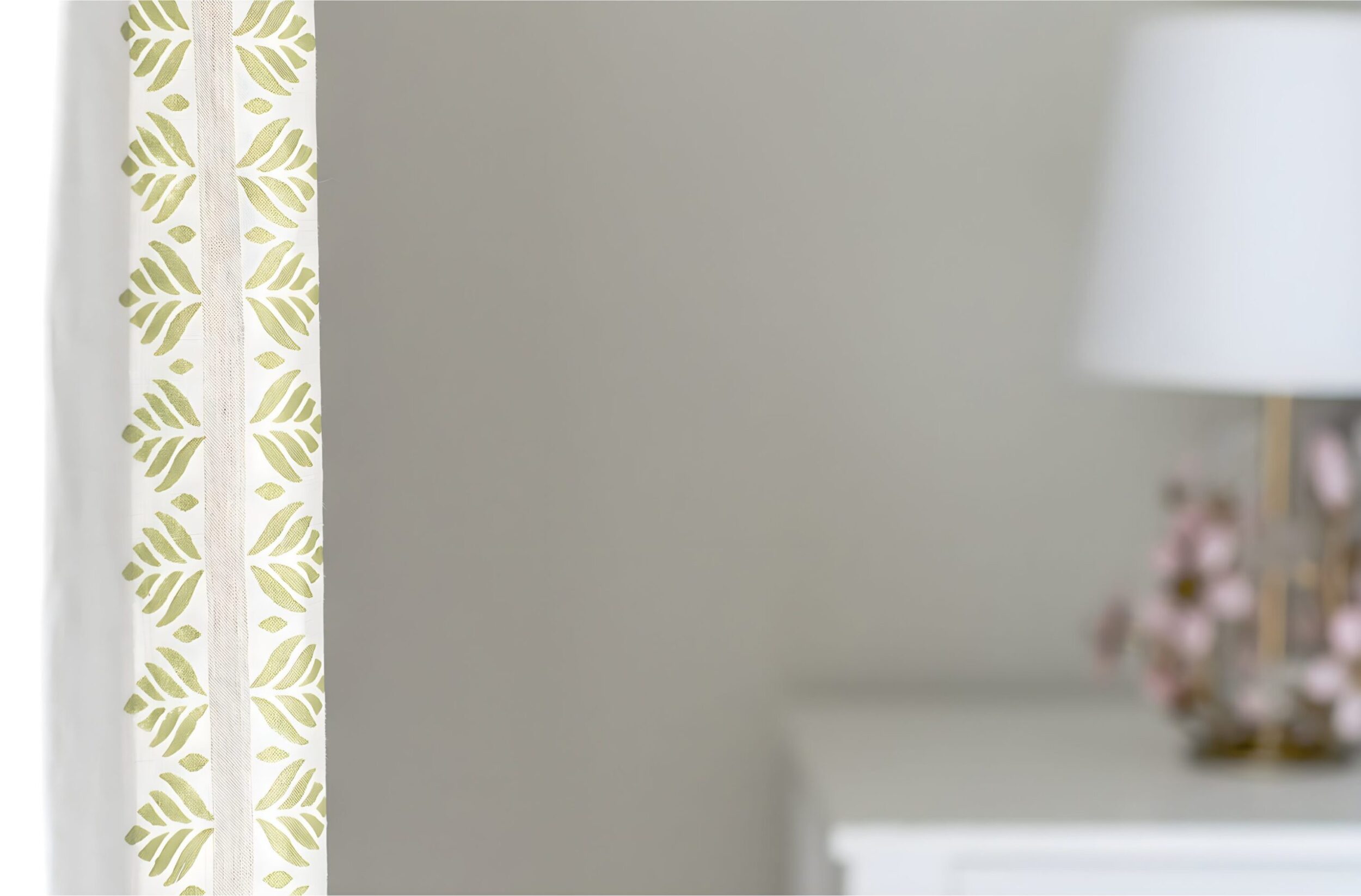 Close-up of kids’ room curtains with embroidered green leaf border on white fabric for custom window textiles