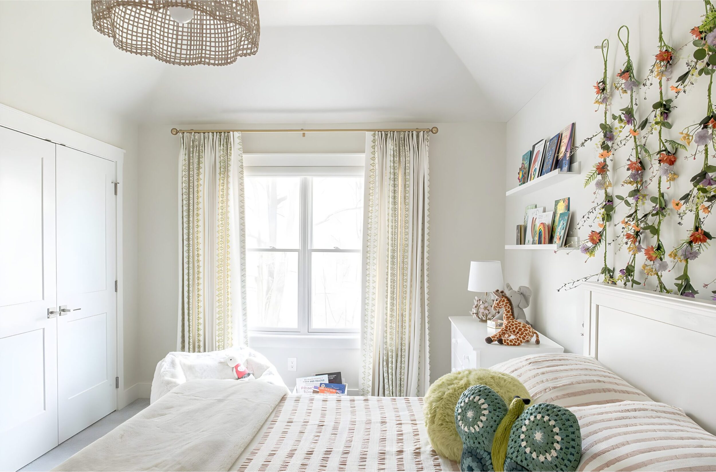 Bright kids’ bedroom with striped bedding, butterfly pillow, floral wall garland, and framed art gallery