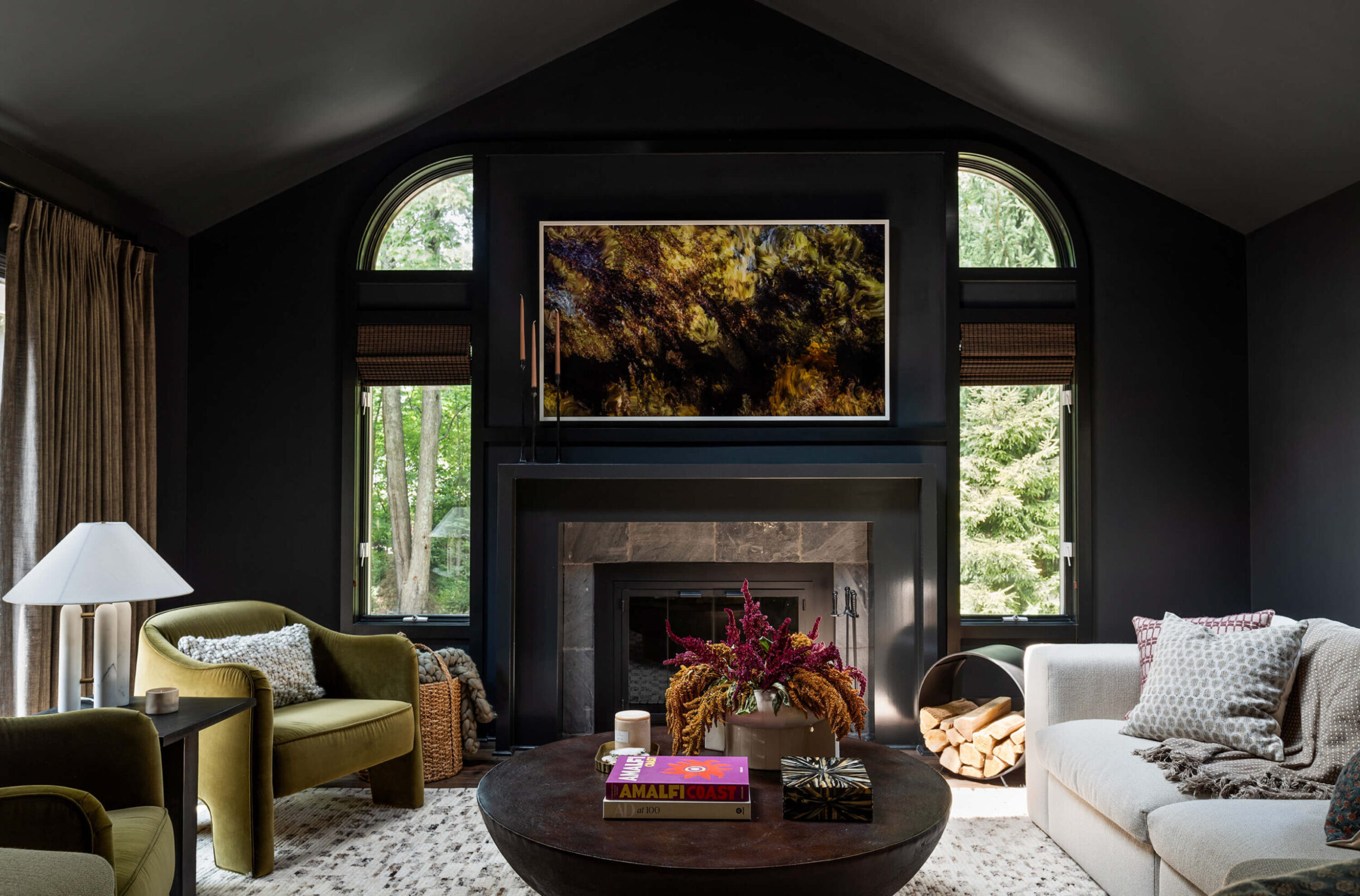 Living room with vaulted ceiling, dark fireplace wall, large art piece, and neutral sofa with patterned pillows.