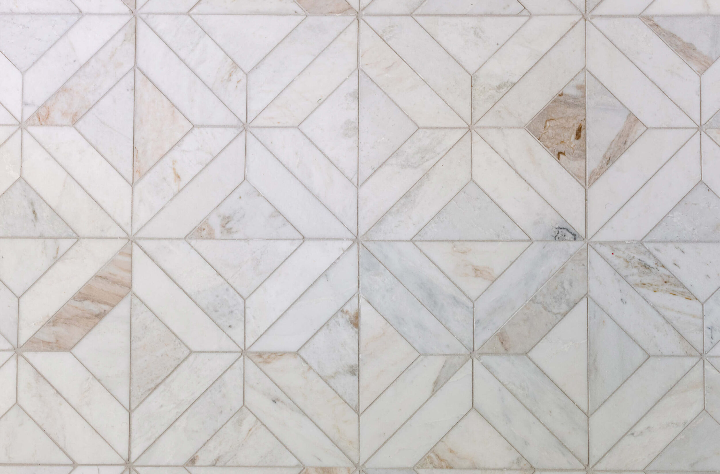 A close-up of a marble Wall with a diamond-patterned tile design in white and beige tones.